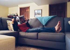 A man relaxing on the couch, reading a magazine while local movers NJ do their job