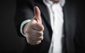 A man in a black suit giving a thumbs up..