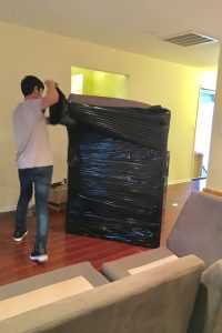 One of our movers Hudson County NJ wrapping a large piece of furniture