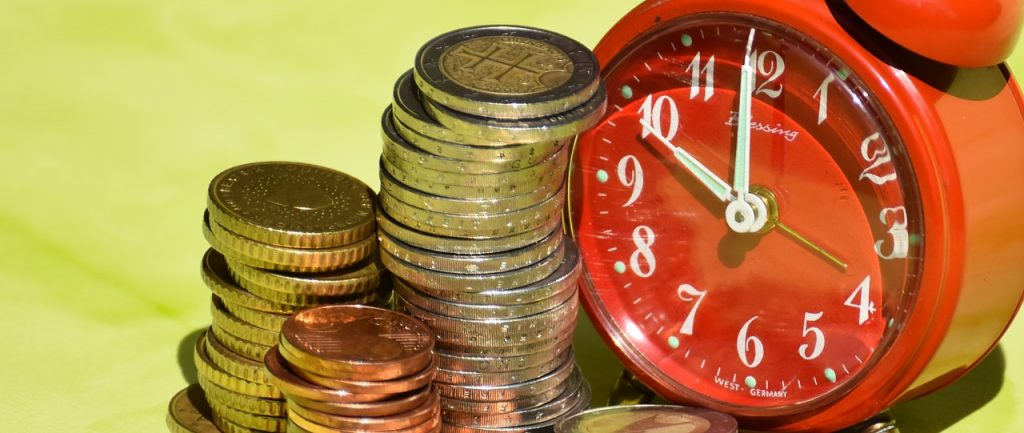 A red clock next to a lot of metal coins