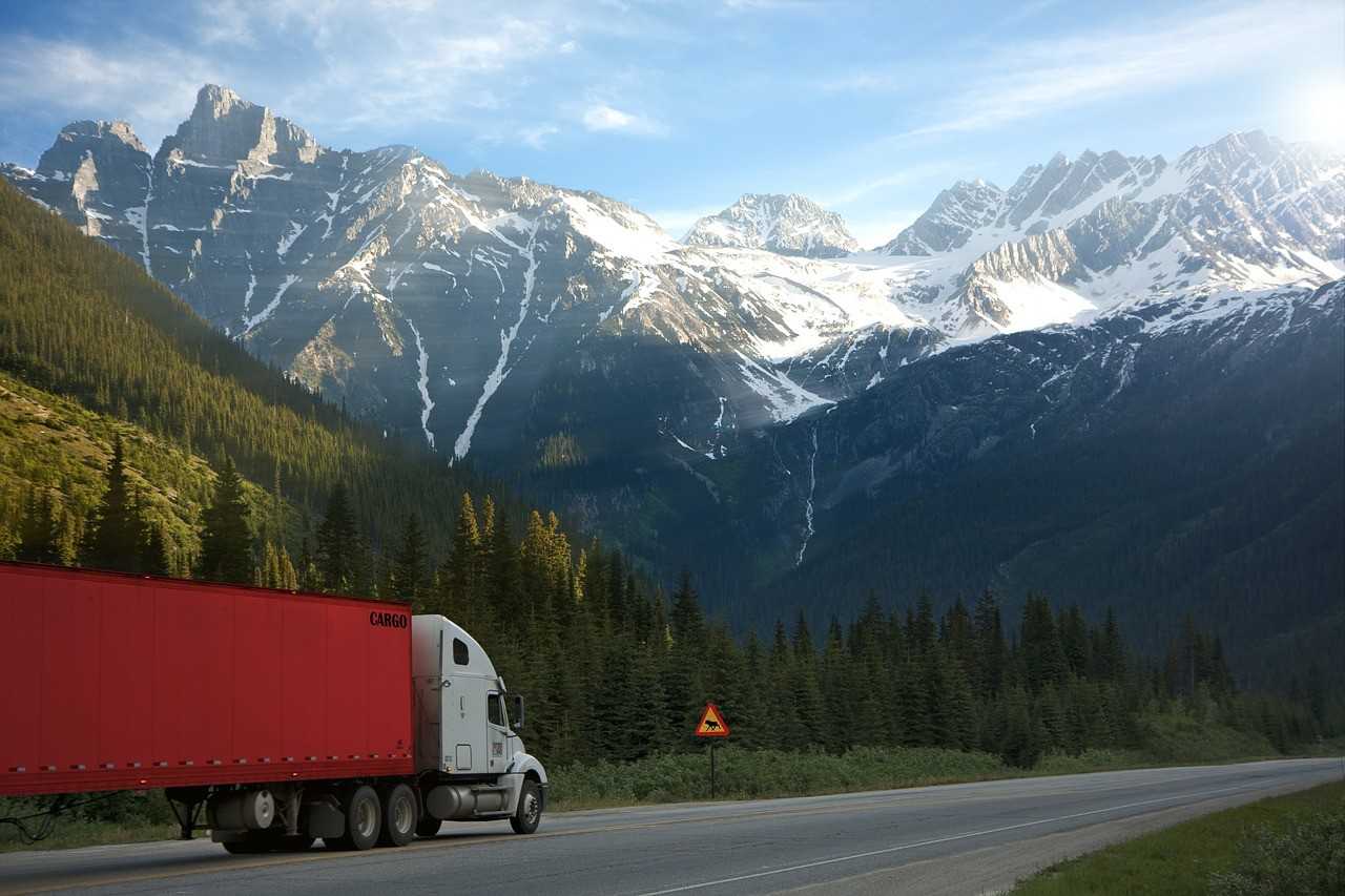 A moving truck marked as cargo on the road, mountains covered with snow in the background