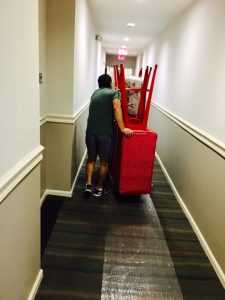 A mover from Bloomfield moving furniture down a narrow hallway