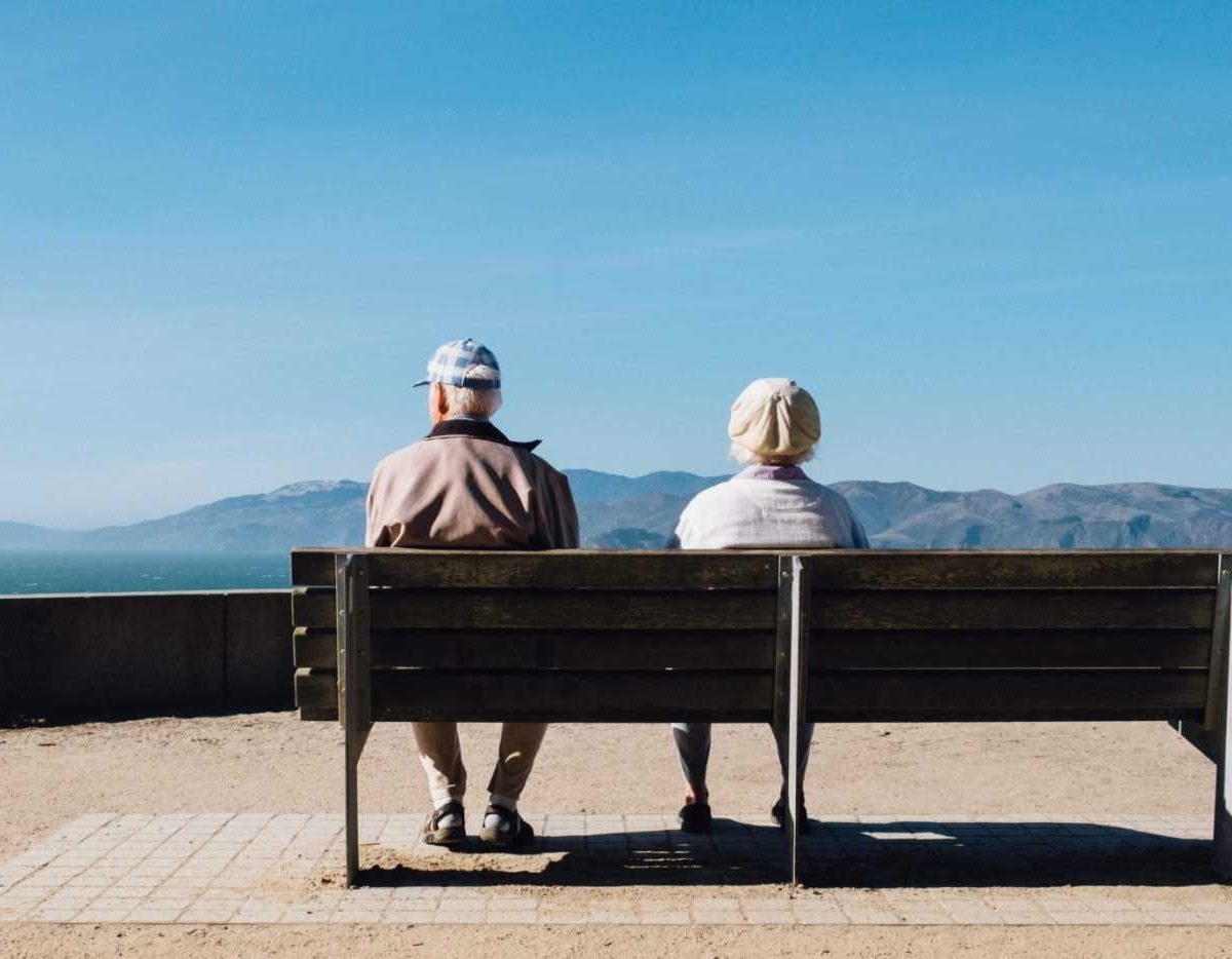A couple of senior citizens sitting on a bench