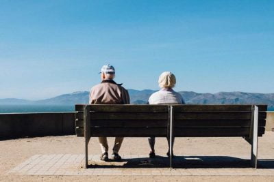 A couple of senior citizens sitting on a bench
