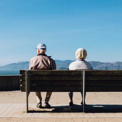 A couple of senior citizens sitting on a bench