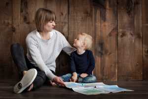 A woman talking to her son while sitting on the floor and holding a map - prepare your child for a move by explaining everything to him.