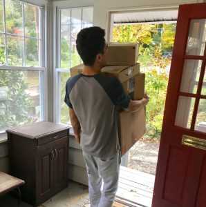 A man carrying boxes through the front door