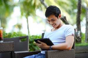 A young man smiling while holding a tablet and learning interesting facts about Essex County