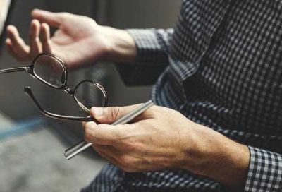 Man holding glasses and pen