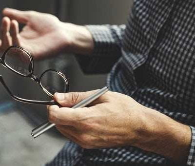 Man holding glasses and pen