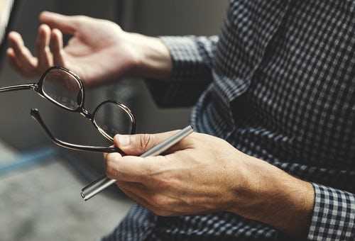 Man holding glasses and pen