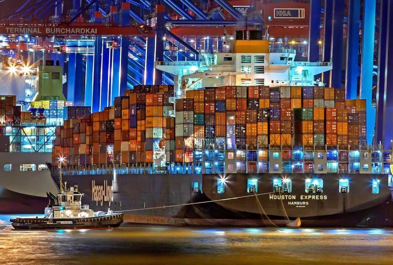 Hamburg port - a large ship full of cargo and a small boat next to it