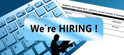 A male silhouette holding newspapers, "We're hiring" written across the picture, a keyboard and an employment application form in the background