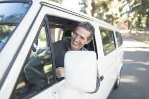 Man smiling while driving car because he has purchased the right type of moving insurance